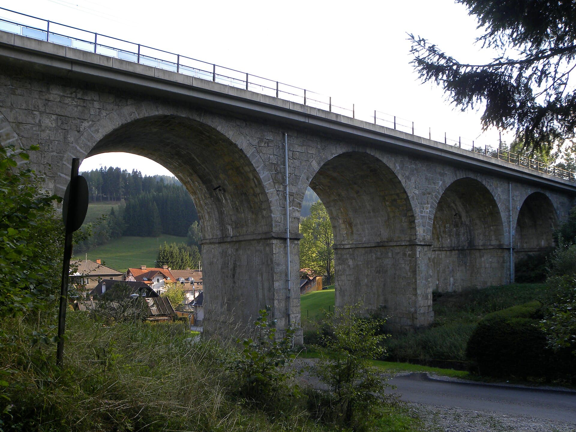 Eine steinerne Brücke der Semmeringbahn, zwischen Wald und Talhängen.
