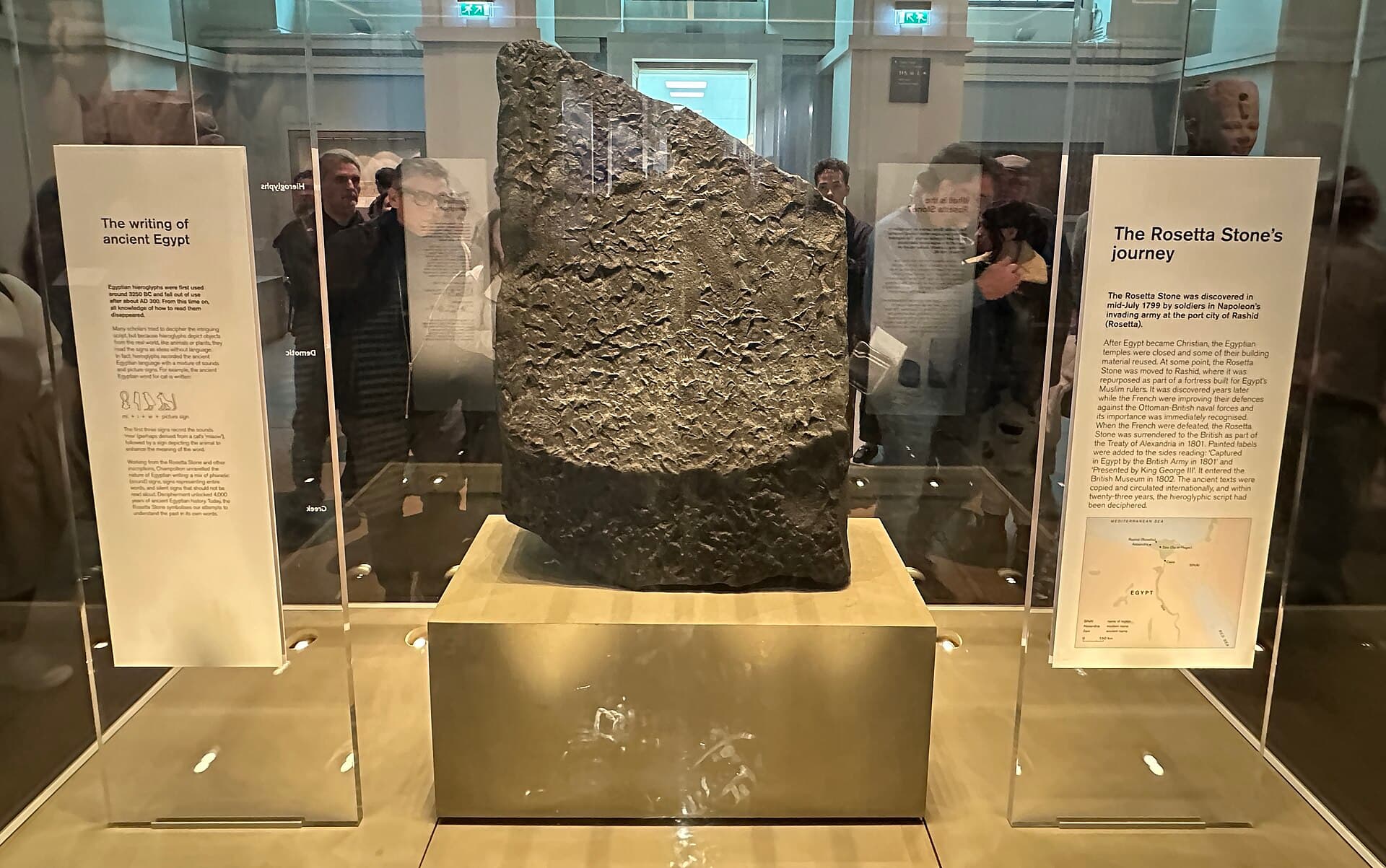 Тёмный Розеттский камень в стеклянной витрине Британского музея.