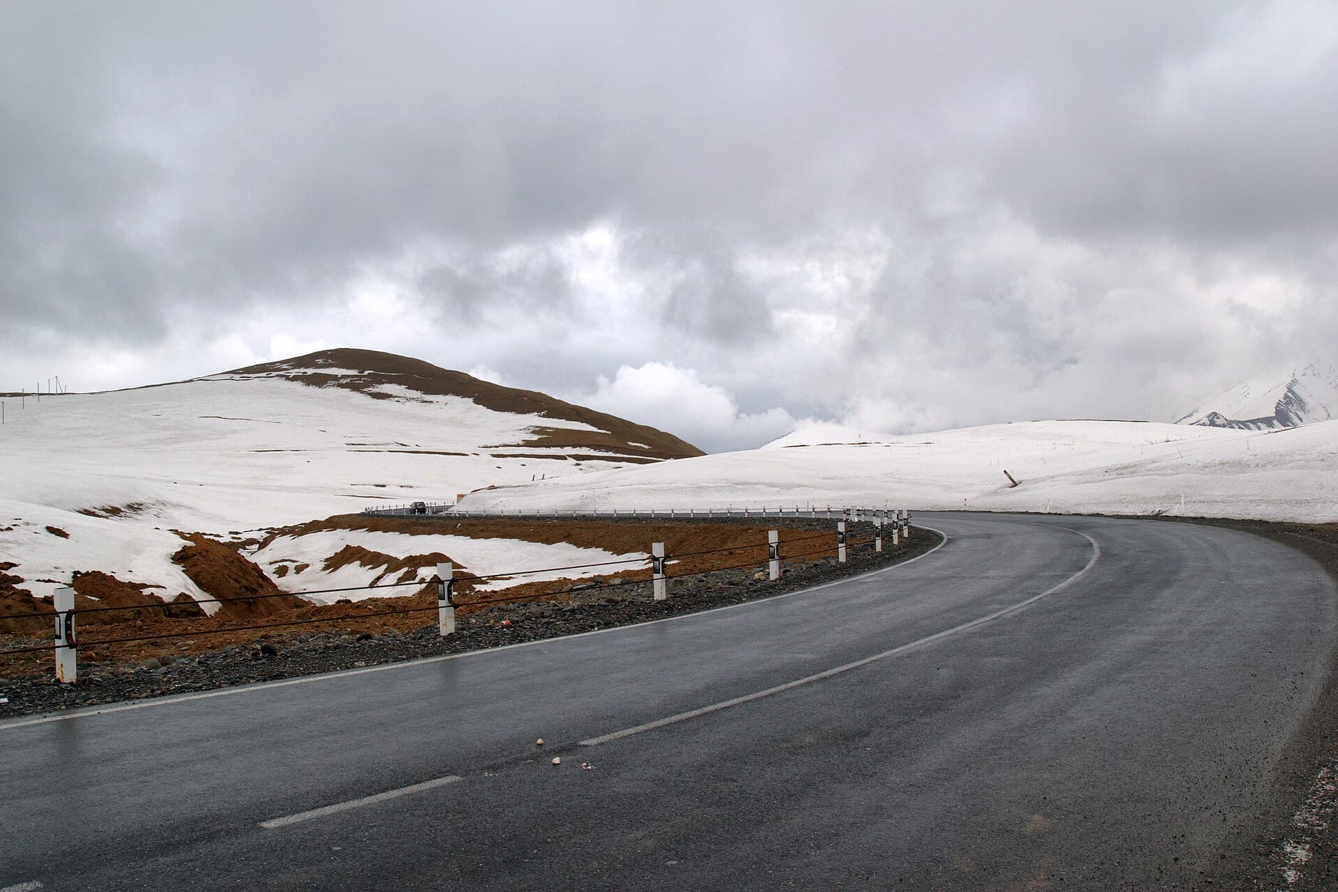Die Georgische Heerstraße windet sich am Kreuzpass zwischen verschneiten Hängen.