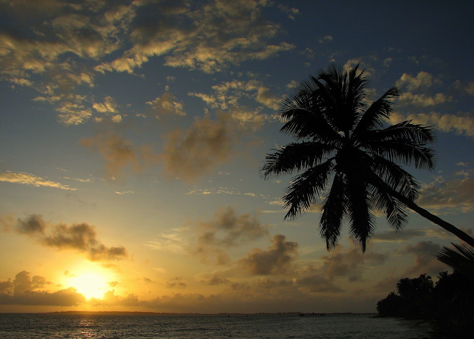 Sonnenaufgang auf dem Atoll Addu, warmes Licht auf ruhigem Wasser.