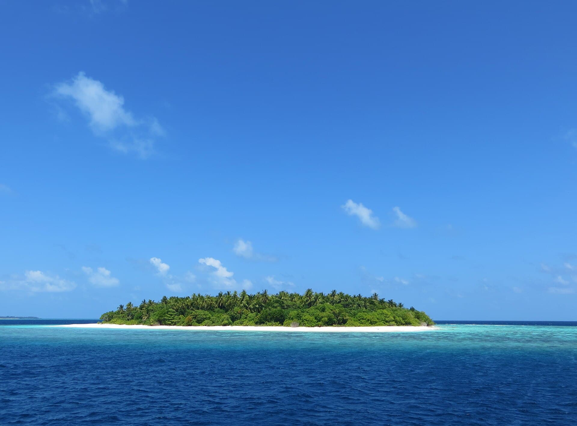 Eine kleine Insel im Atoll Baa aus geringer Höhe, ein Sandring in der Lagune.