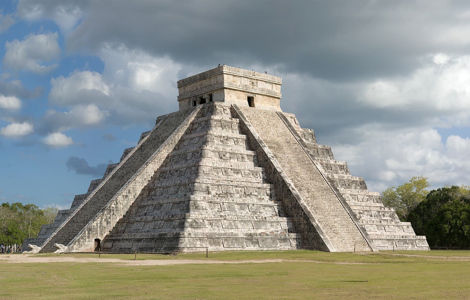 Chichén Itzá'da dört merdivenli, tepesinde tapınak olan basamaklı Kukulkan Piramidi, yoğun bulutlar altında.