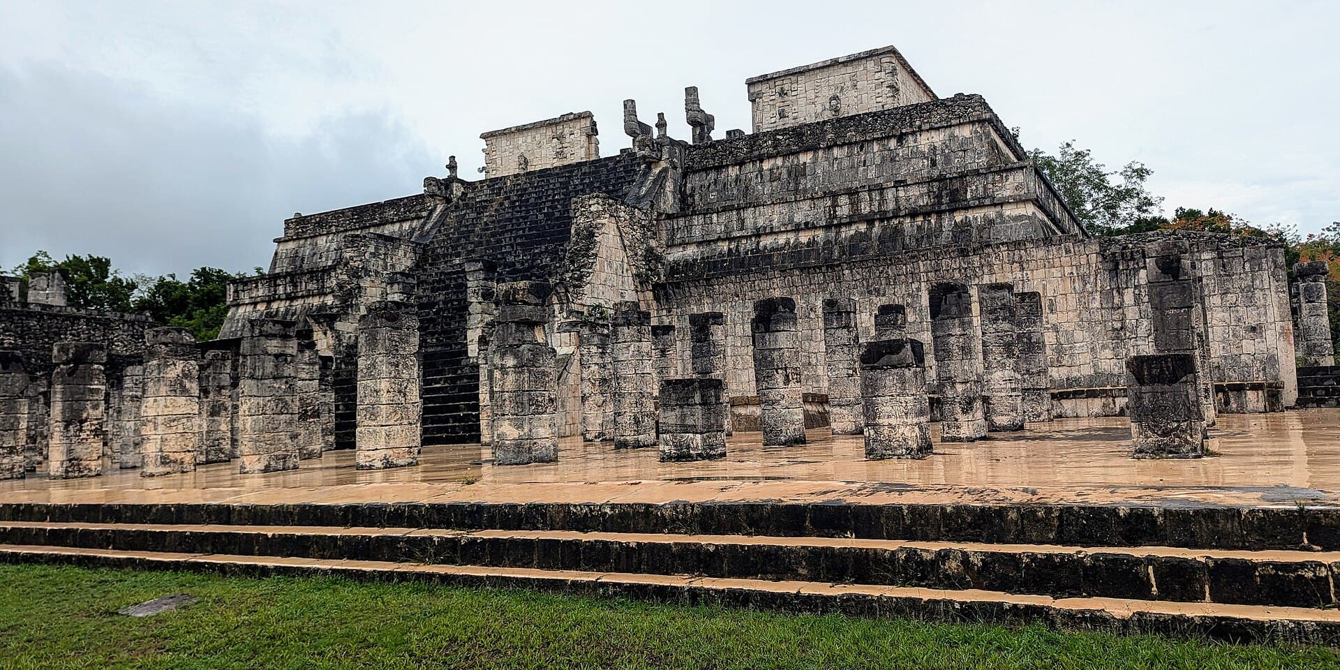 Chichén Itzá'da basamaklı bir platform üzerindeki Savaşçılar Tapınağı ve önündeki taş sütun sıraları.