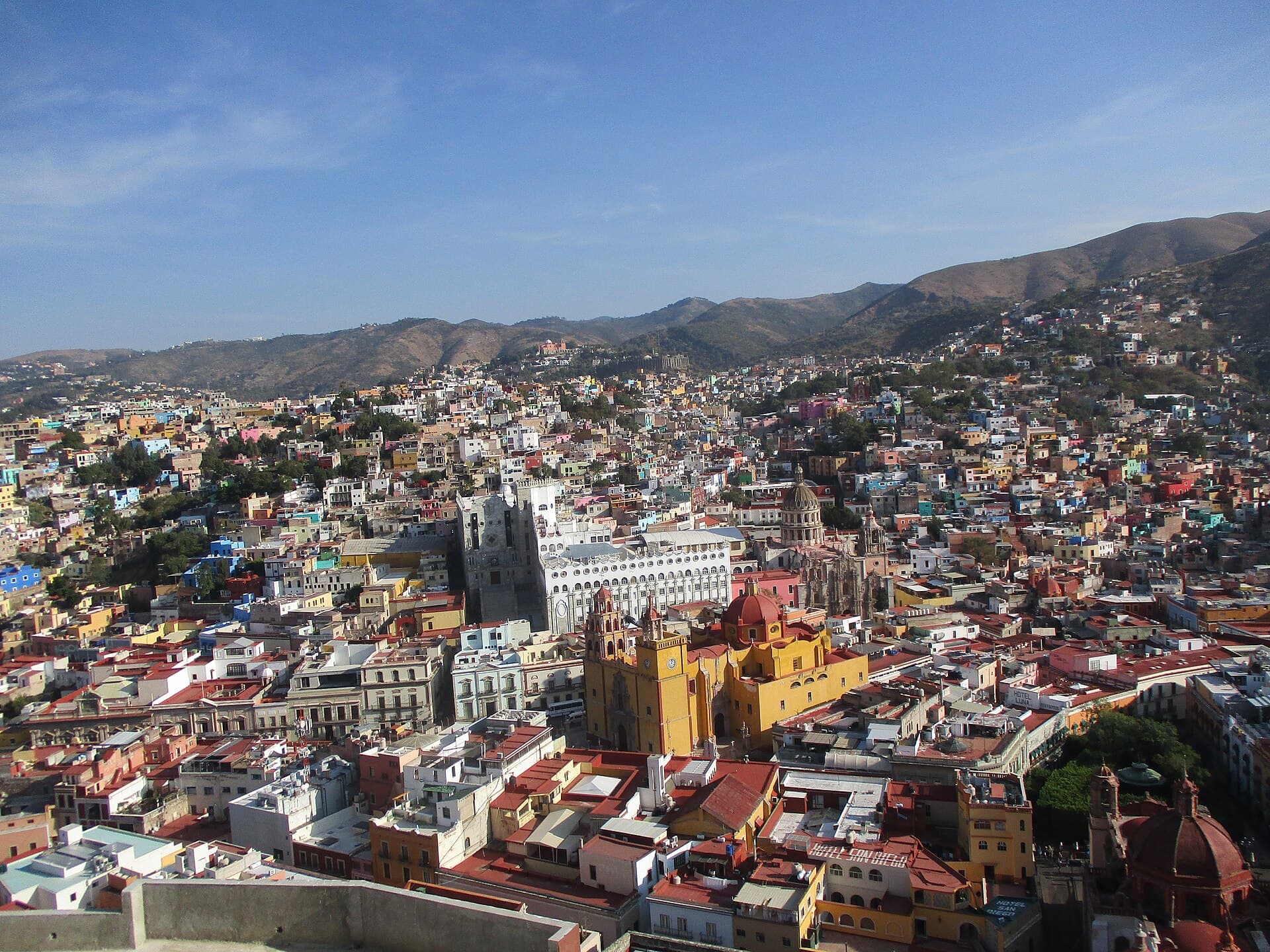 Guanajuato from above, its painted neighbourhoods climbing the mountainsides under a blue sky.