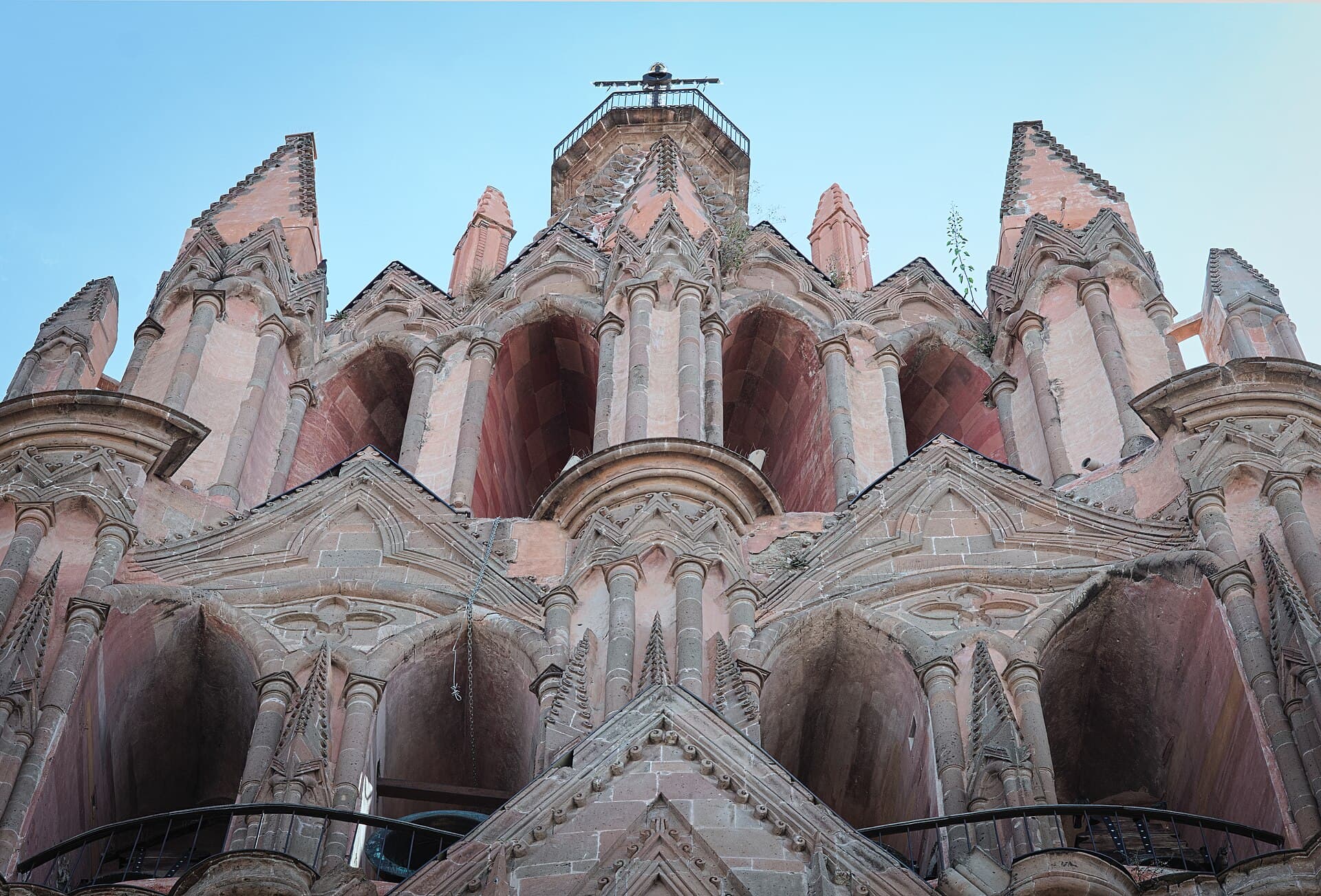 The pink, pointed towers of San Miguel's parish church seen from below, thick with stone carving.