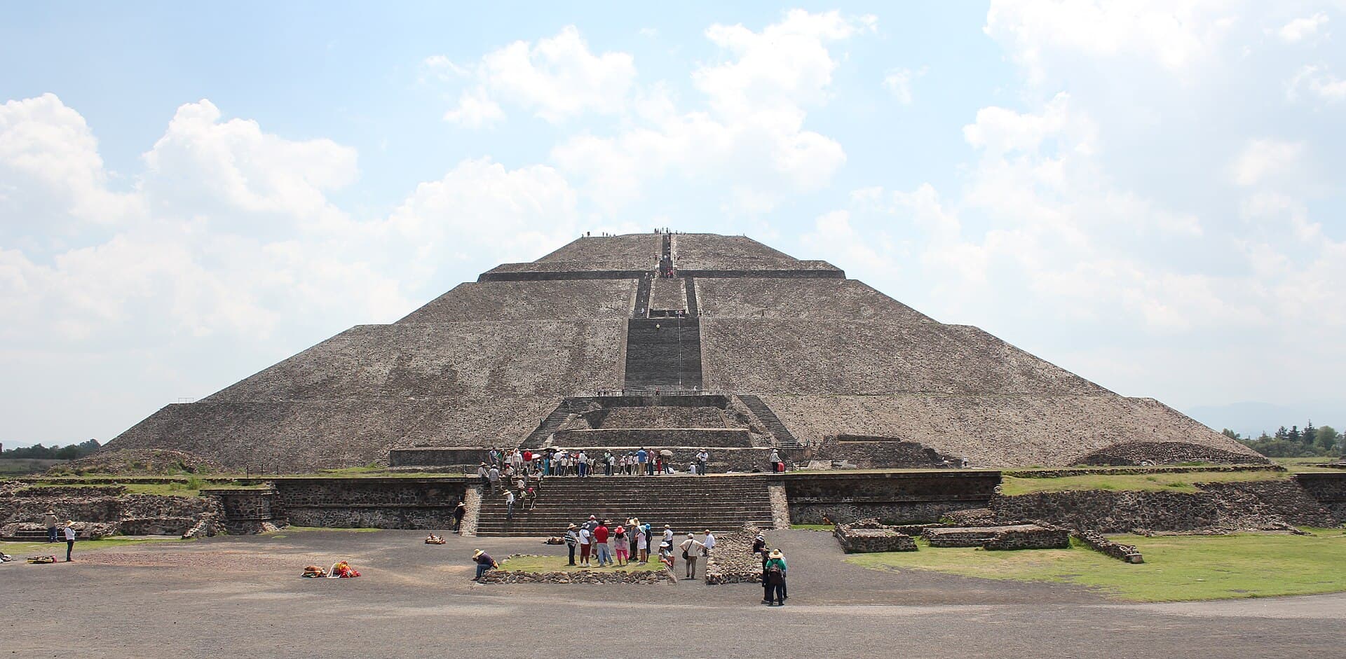 The broad Pyramid of the Sun at Teotihuacan with its central stairway under white clouds.
