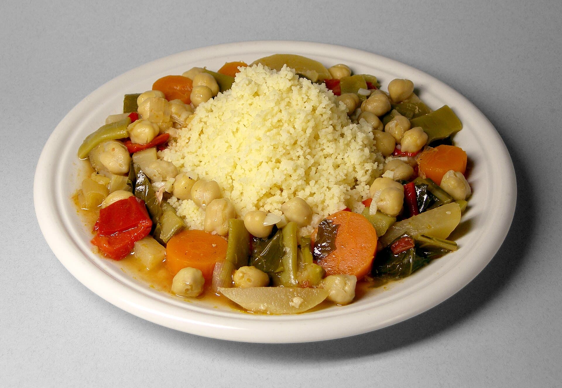 Ein Teller Couscous mit Kichererbsen, Gemüse und Fleisch.
