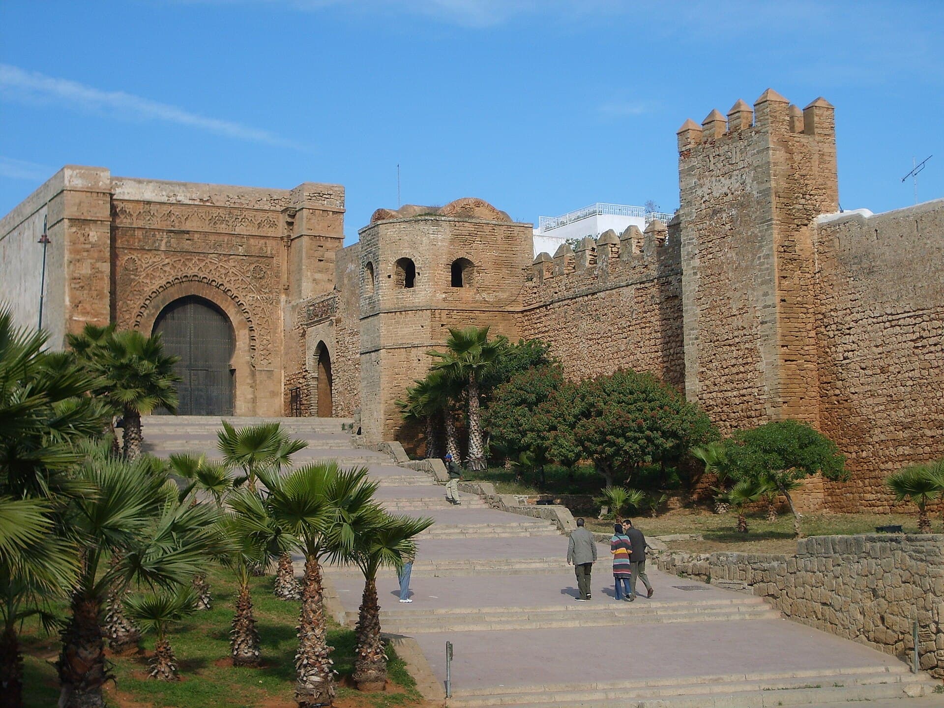 Tor und Steinmauern der Kasbah der Oudaya zwischen Palmen.