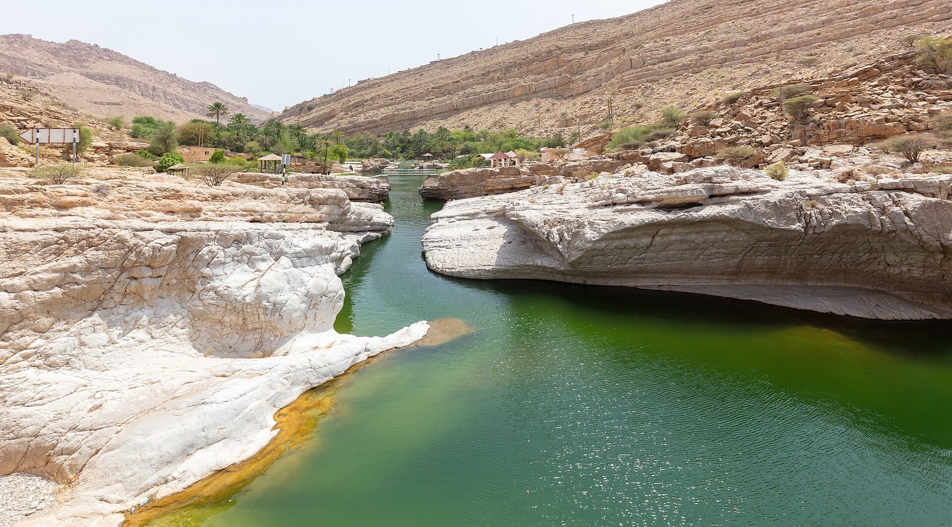 مجرى ماء أخضر بين صخور ملساء بيضاء في وادي بني خالد.