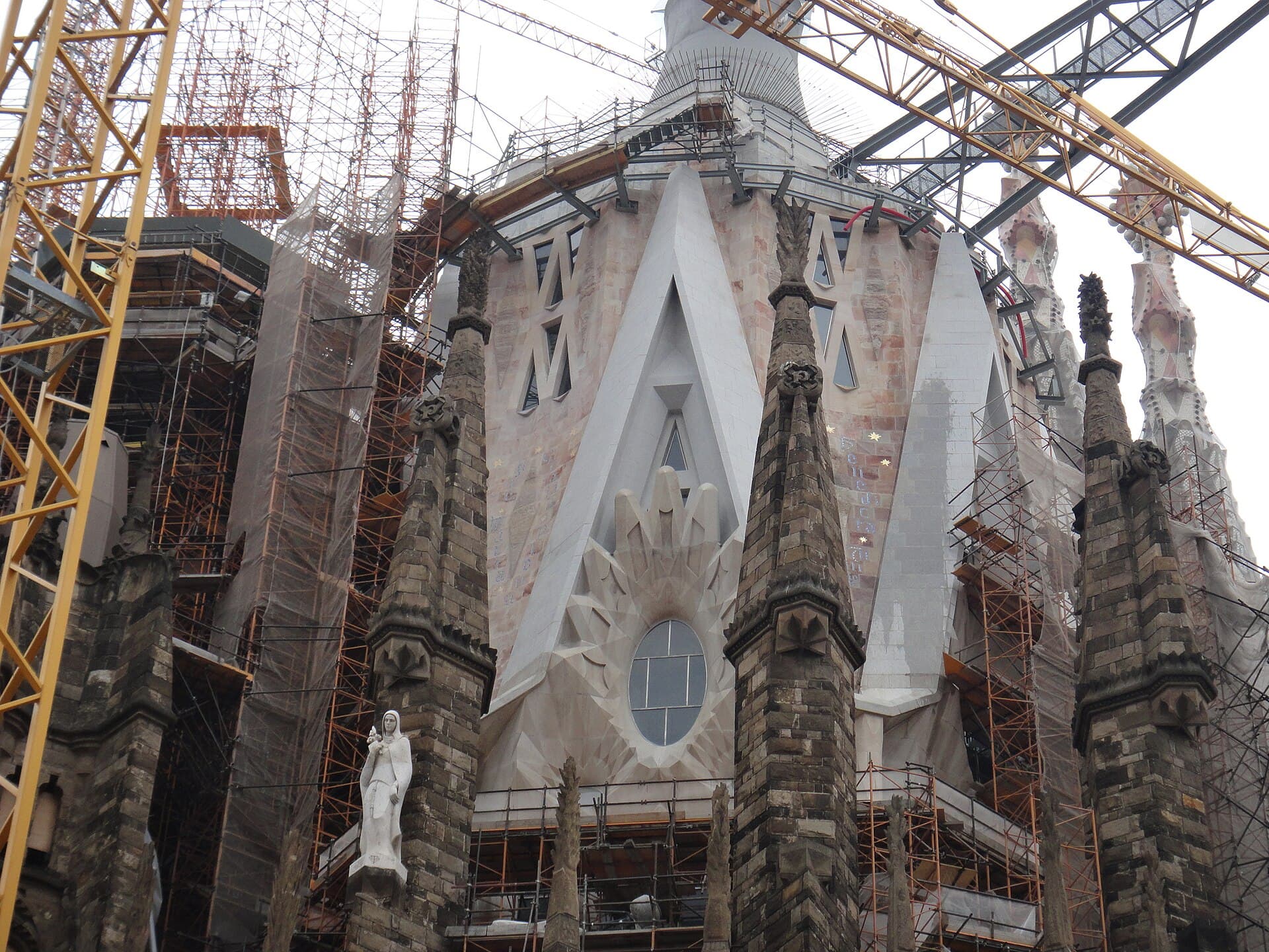 The towers of the Sagrada Família with cranes above them, the building still underway.