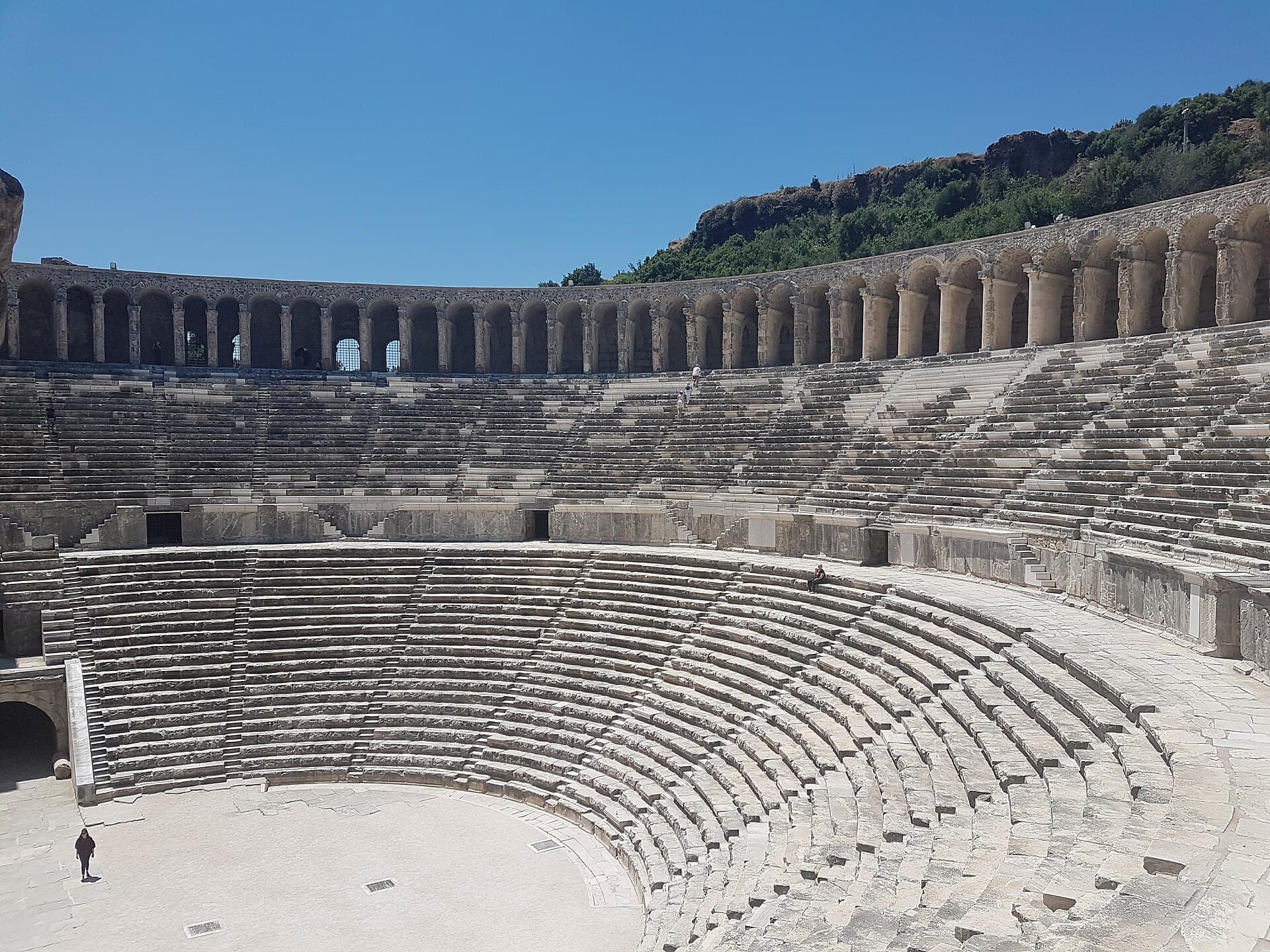 Zuschauerränge und obere Arkaden des römischen Theaters von Aspendos unter klarem Himmel.