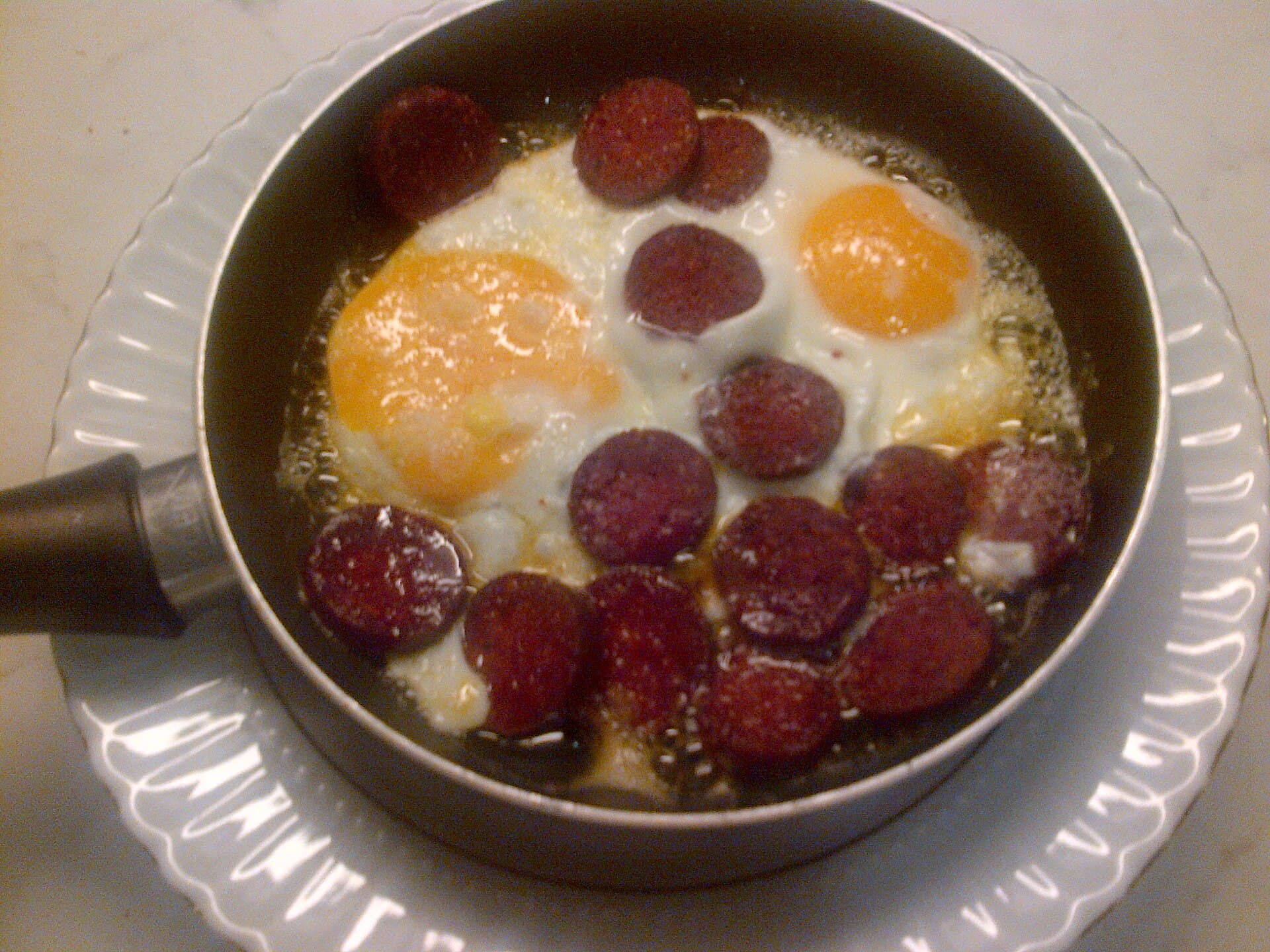 Eine kleine Pfanne mit Spiegeleiern und Sucuk-Scheiben, ein türkisches Frühstücksgericht.