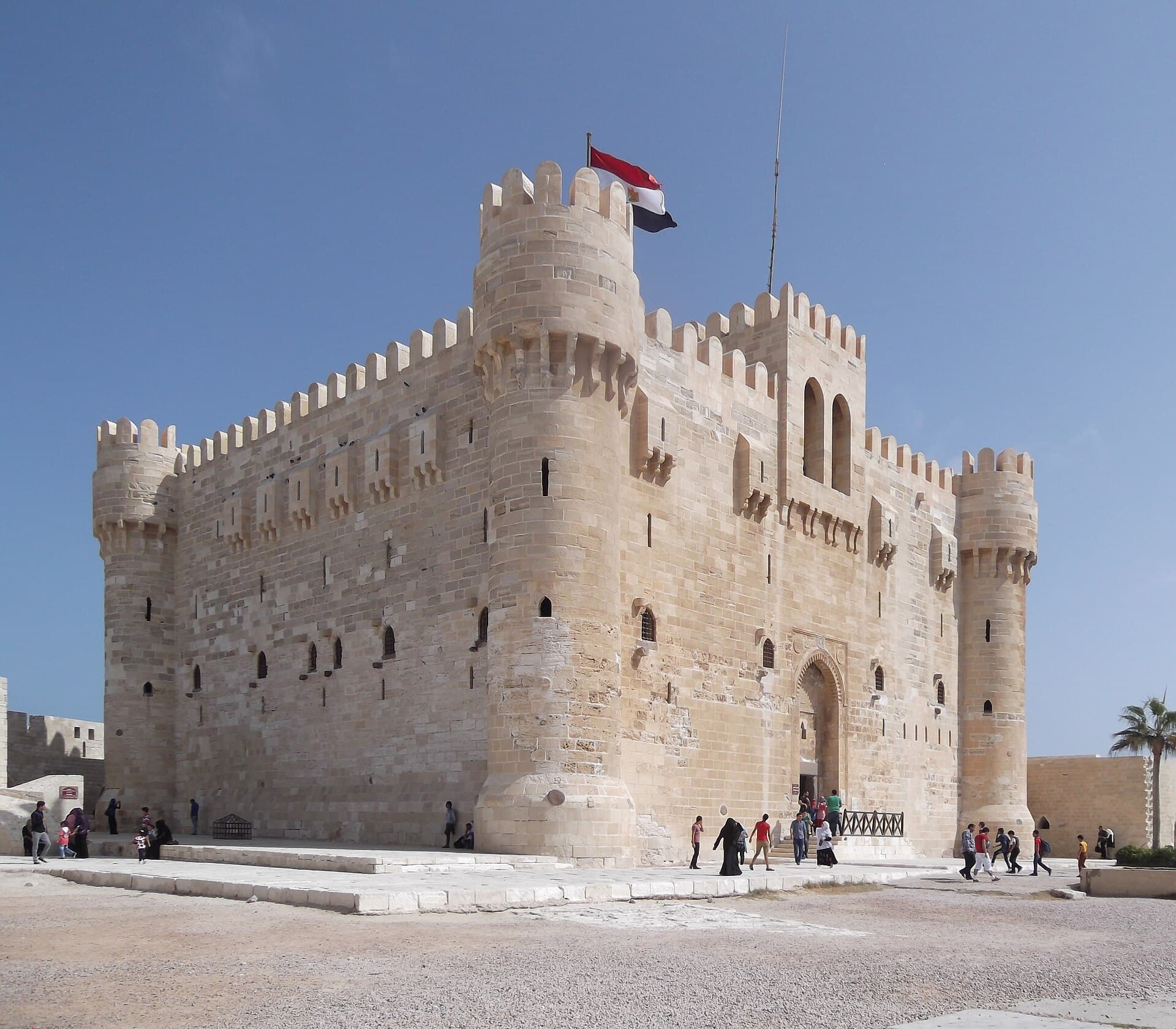 Steintürme und Mauern der Zitadelle des Qaitbay an der Küste von Alexandria unter blauem Himmel.