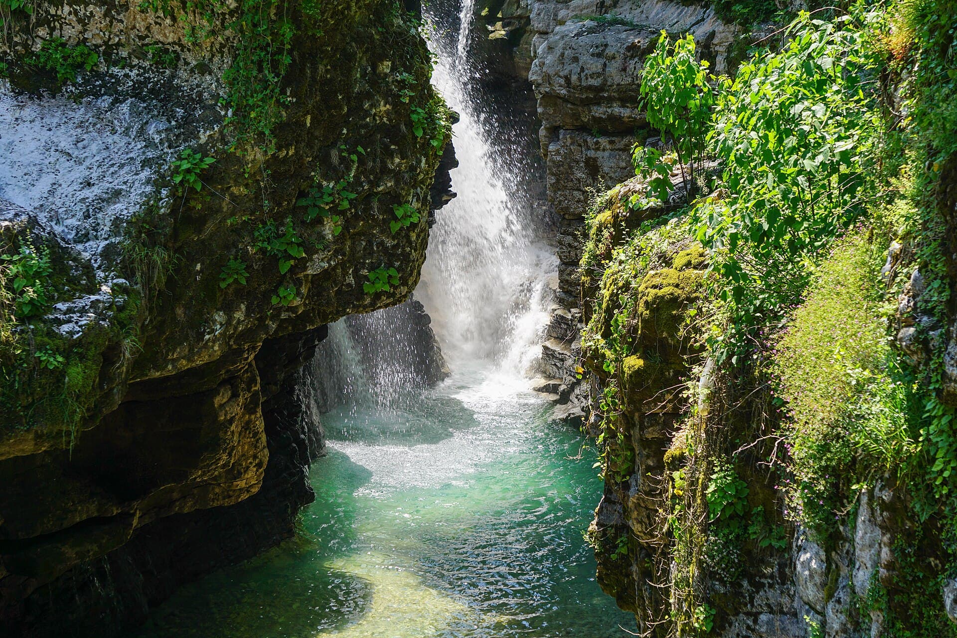 Ein Wasserfall stürzt zwischen Felsen der Martwili-Schlucht in ein türkises Becken.