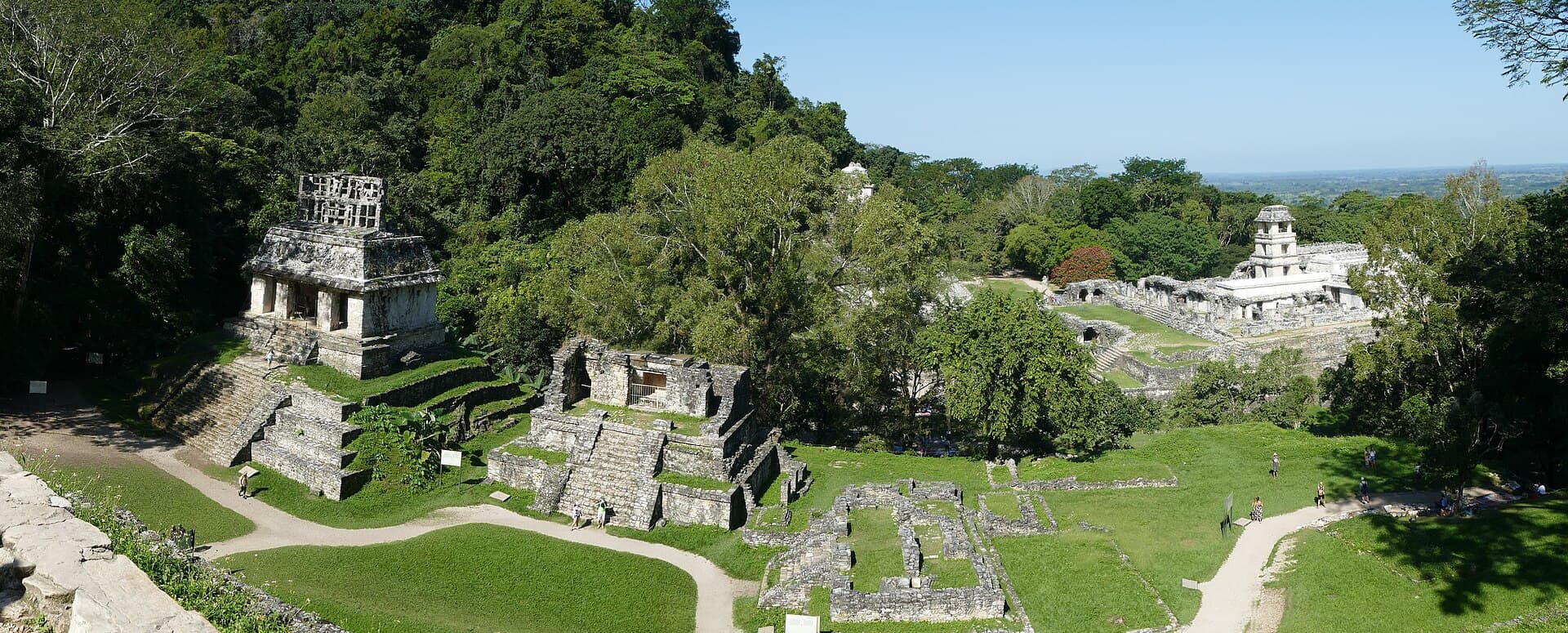 Die Steintempel von Palenque zwischen Bäumen, links der Sonnentempel, rechts der Palast.