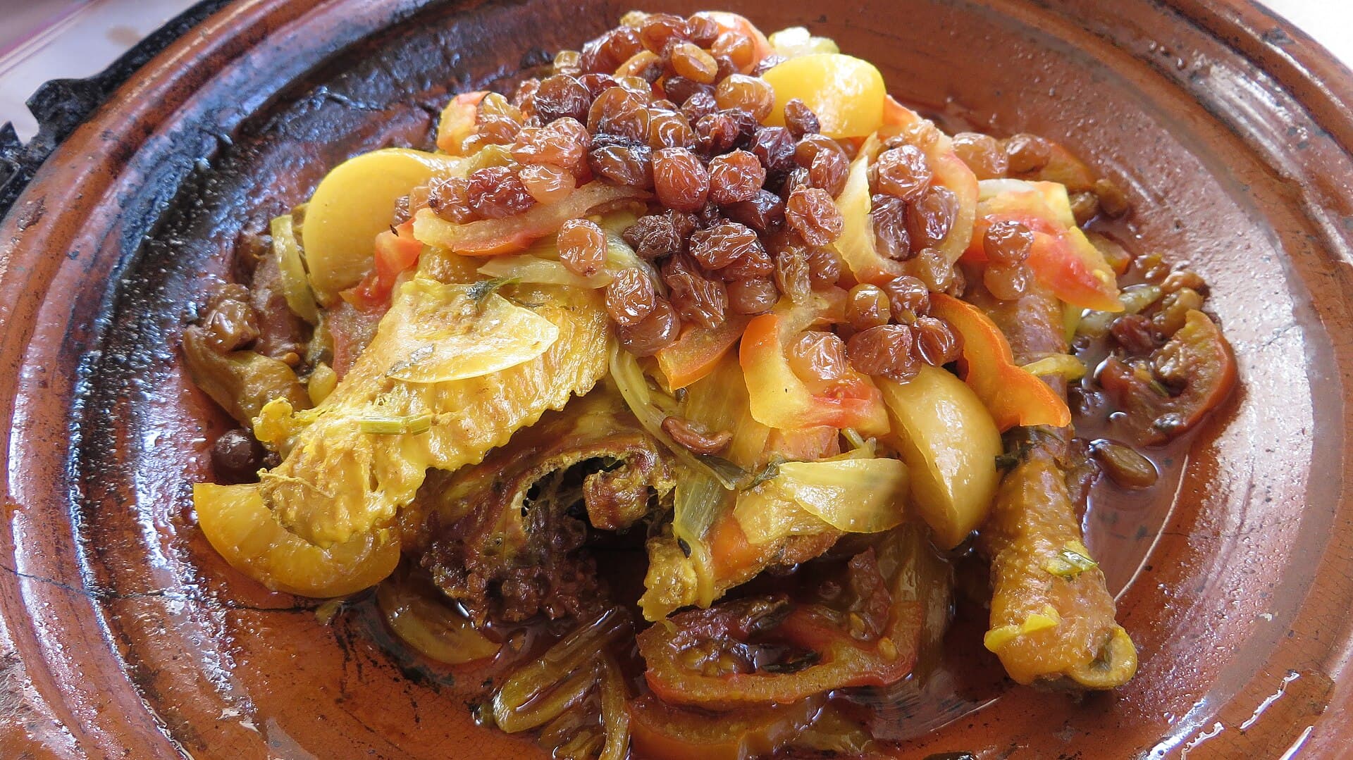 Eine Hähnchen-Tajine mit Trockenfrüchten und Rosinen im Tontopf.