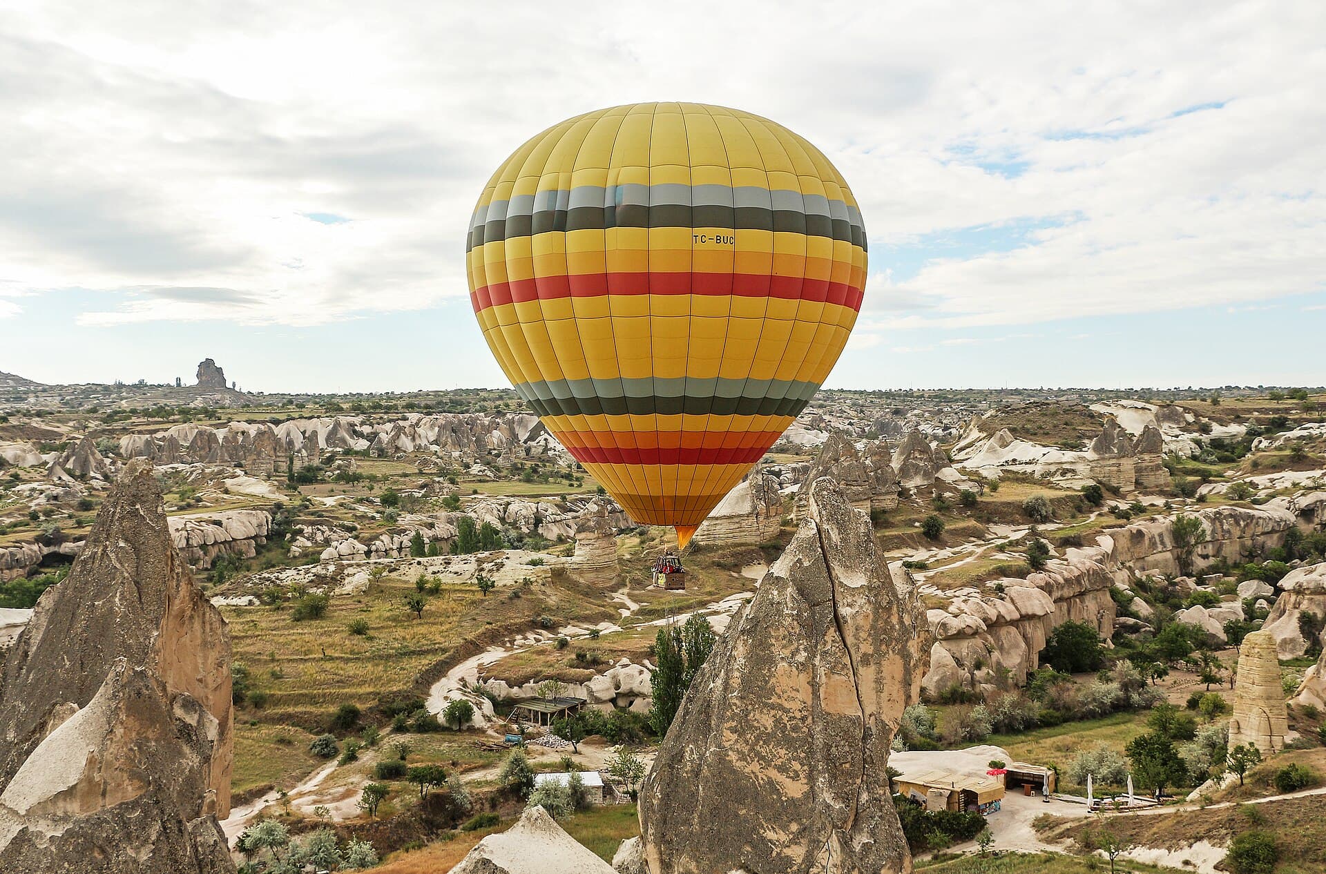 Ein gestreifter Heißluftballon schwebt über den Tälern und Felssäulen Kappadokiens.