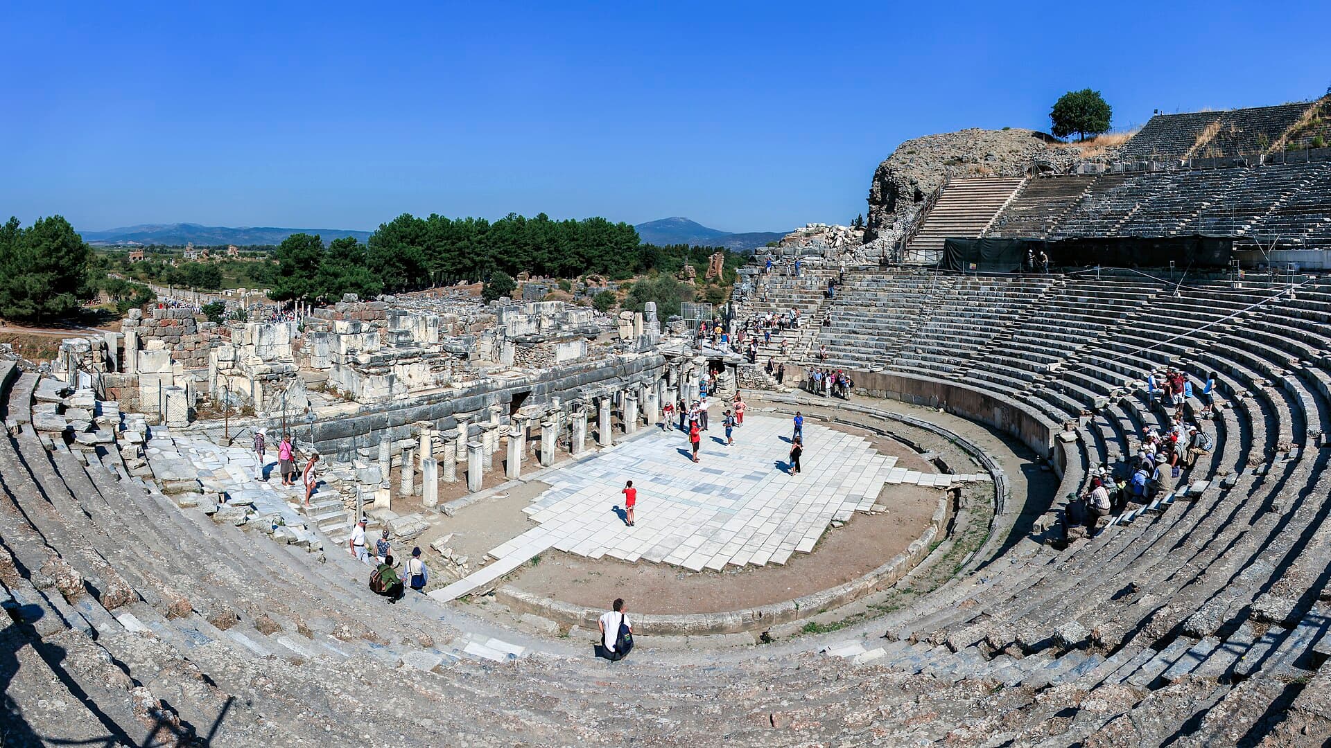 Das große Theater von Ephesos mit halbrunden Rängen, dahinter die antike Straße.