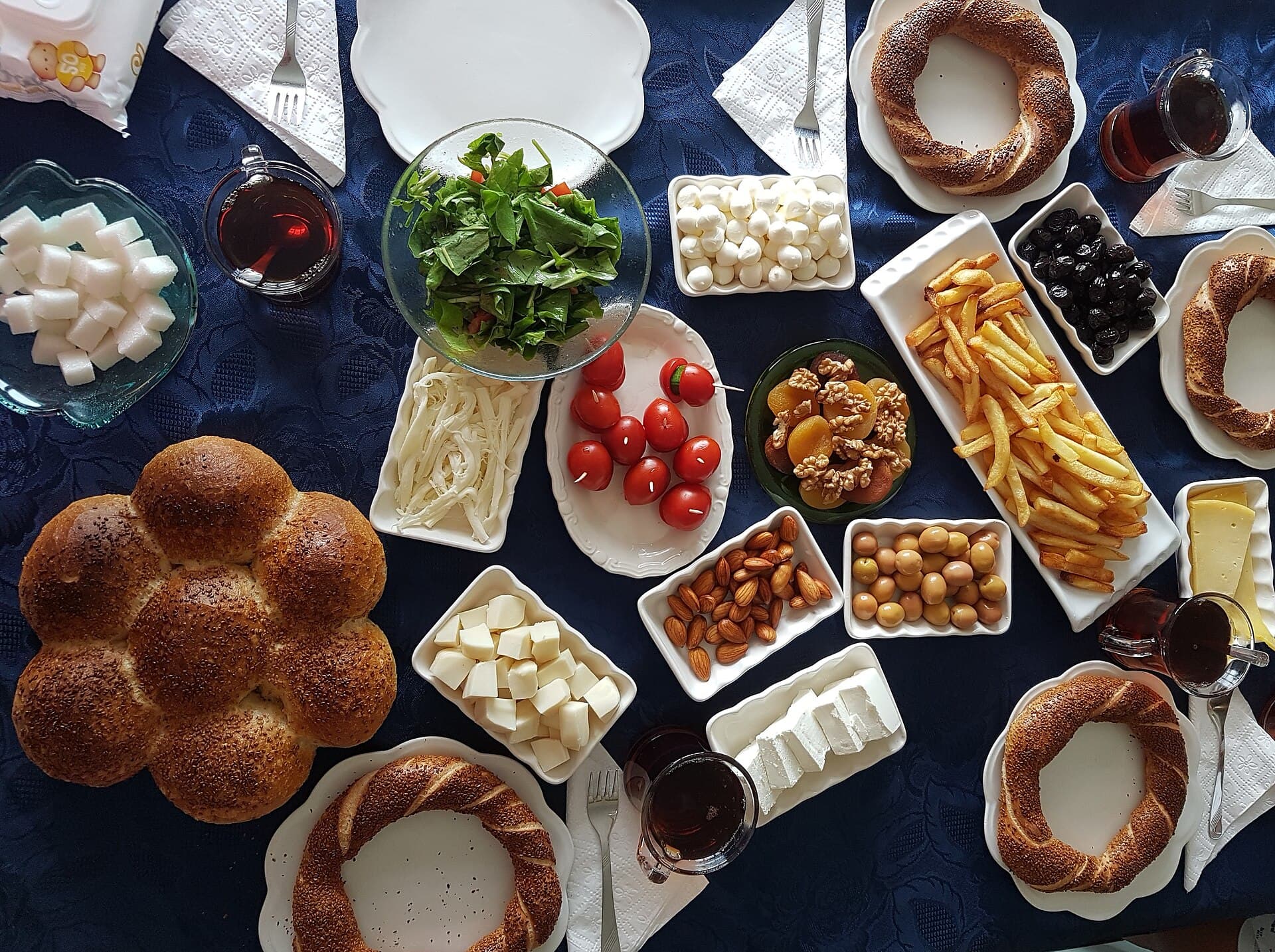 Ein türkischer Frühstückstisch mit Käse, Oliven, Tomaten und Marmeladen, dazu Simit-Ringe und Brot.